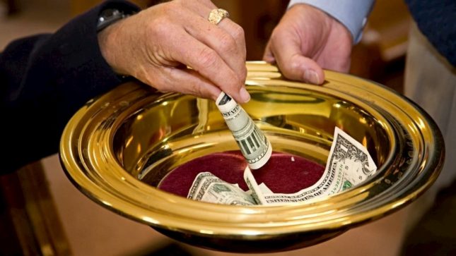 Hands putting money into a gold bowl.