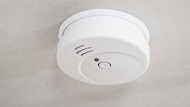 White smoke detector on gray ceiling.