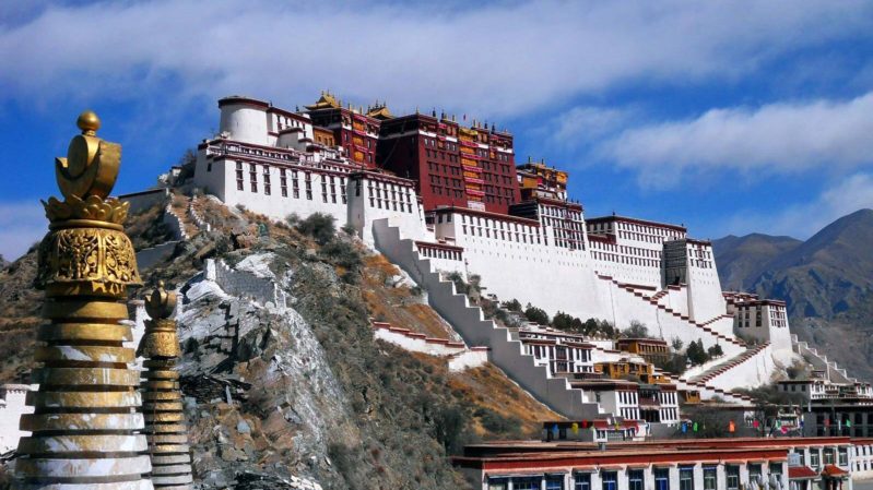 A big castle that is white with an orange roof, there is a blue sky with white clouds.