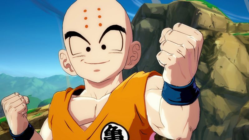 A photo of someone from dragon ball Z, animated cartoon with orange vest on against a blue sky and mountain background. He is bald with six red dots in two vertical lines down his forehead.